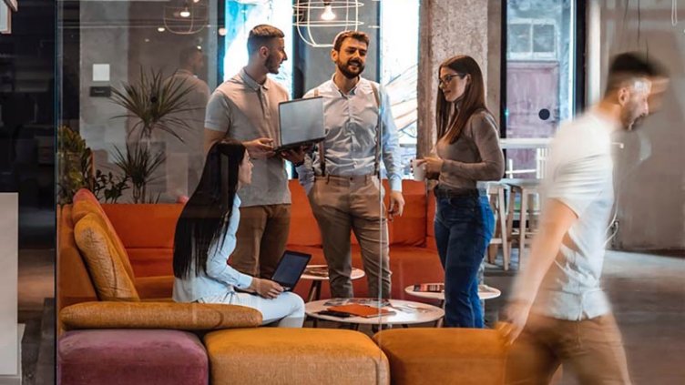 Office space with people in a glass meeting room and other employees working at their desks