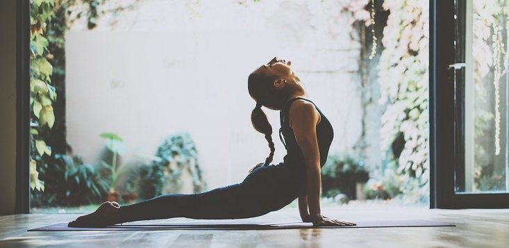 Portrait of gorgeous young woman practicing yoga indoor. Beautiful girl practice cobra asana in class.Calmness and relax, female happiness.Horizontal, blurred background