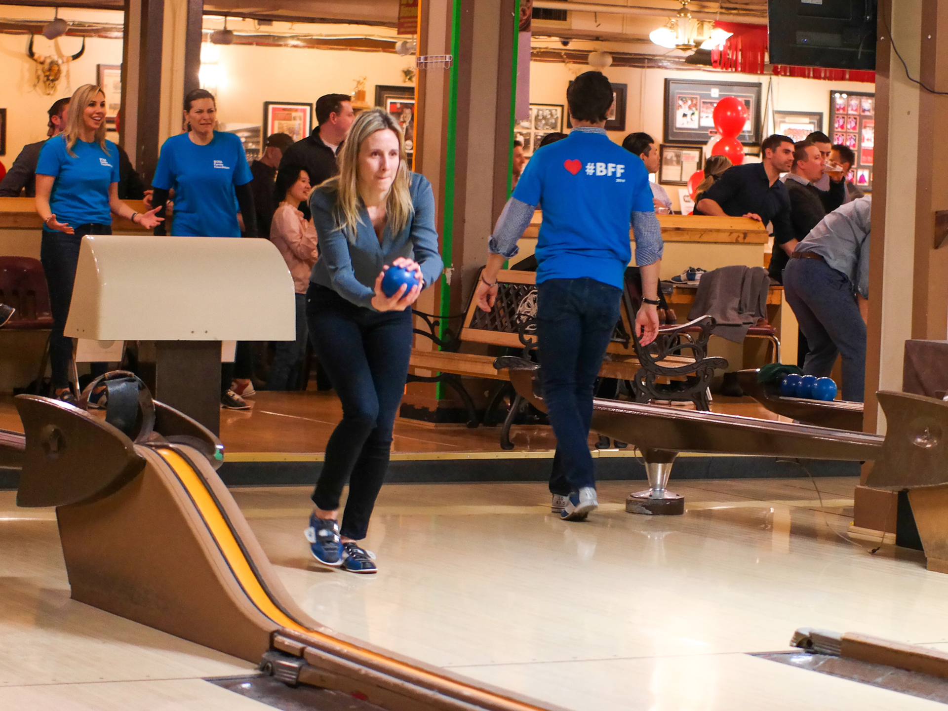 People enjoying in bowling alley and lady throwing ball in the bowling area.