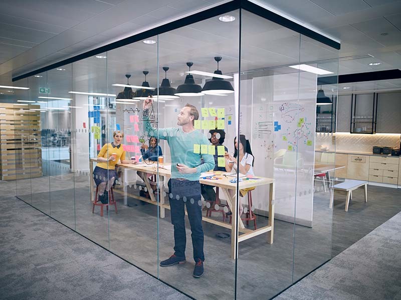 A person is explaining something to the team while writing on a board