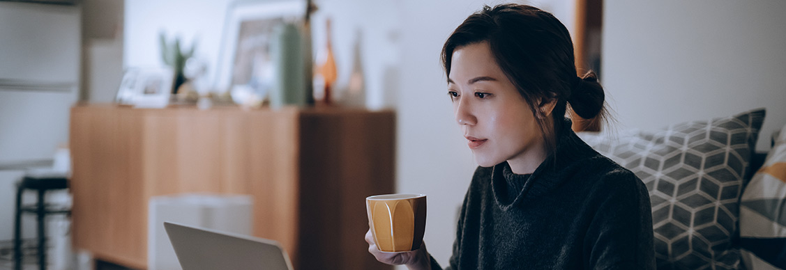 Women employee sitting with her laptop and coffee.