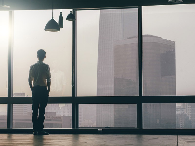 Picture of a man looking towards the real estate buildings through the glass window